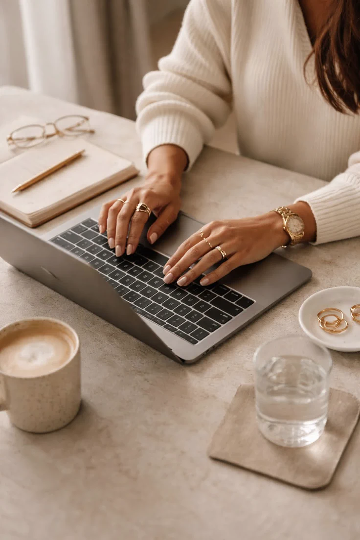 Handen met ringen die typen op een laptop